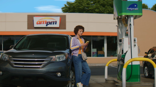 woman leaning on a car looking at her phone