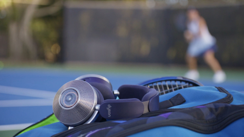 headphones sitting on a bag next to a tennis court